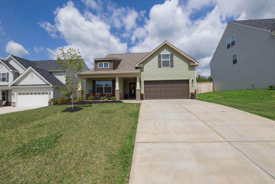 A modern suburban detached house with a spacious driveway under a bright blue sky.