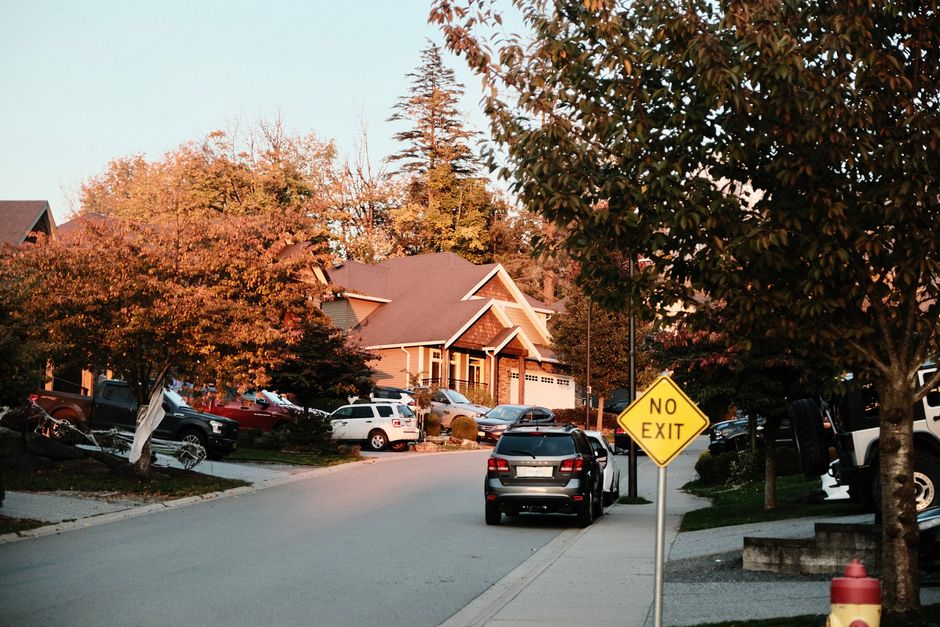 Charming suburban street scene with houses, cars, and a no exit sign in fall.